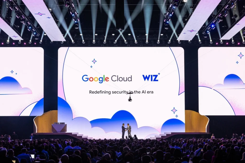 Executives shake hands on the Google Cloud Next keynote stage before a packed audience under cloud-themed screens.