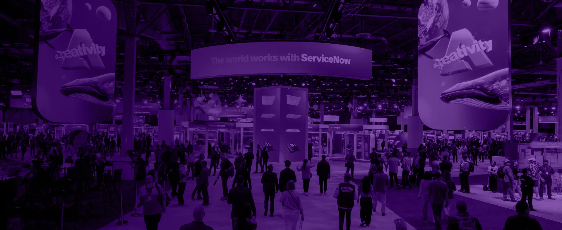 Attendees fill the ServiceNow Knowledge show floor beneath a curved "The world works with ServiceNow" LED banner.