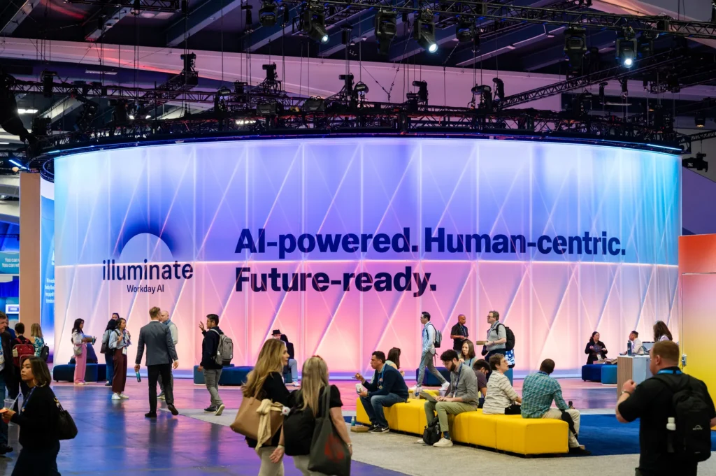 Attendees gather at Workday Rising 2025 before a curved illuminated wall reading "AI-powered. Human-centric. Future-ready."