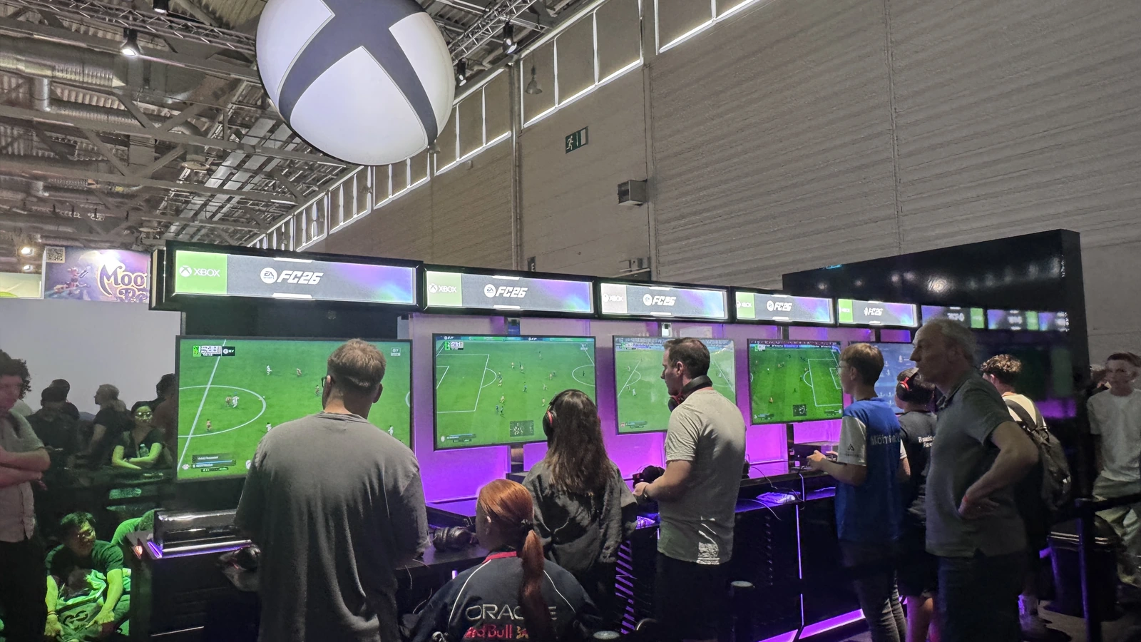 Attendees play EA Sports FC26 at Xbox gaming stations beneath the massive white Xbox sphere suspended over the Xbox booth at Gamescom 2025 in Cologne, Germany — one of the 120 gaming stations Sparks analyzed to produce the Earned Engagement Value (EEV) and 11x return-on-investment metric for Xbox at Koelnmesse.