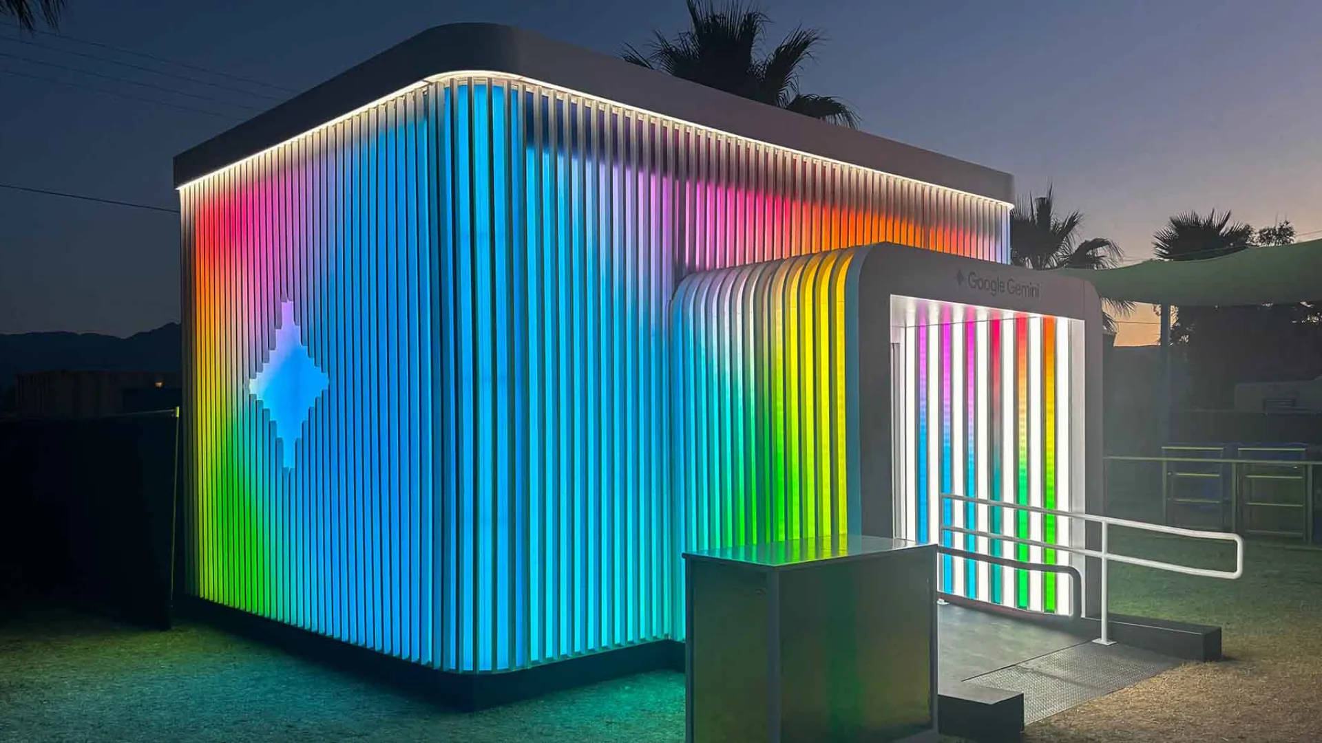 Illuminated rainbow fins and Gemini spark on the activation exterior after dark
