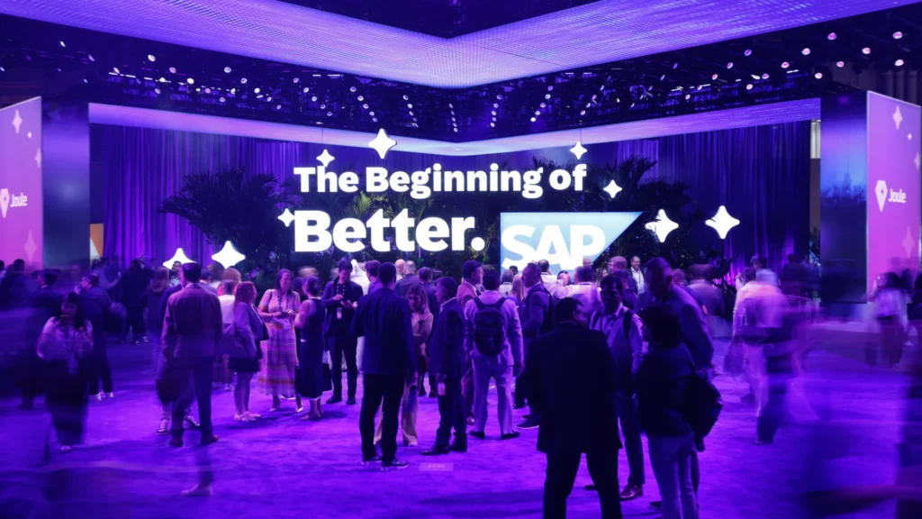 Crowd gathers beneath The Beginning of Better display, flanked by Joule branded LED towers