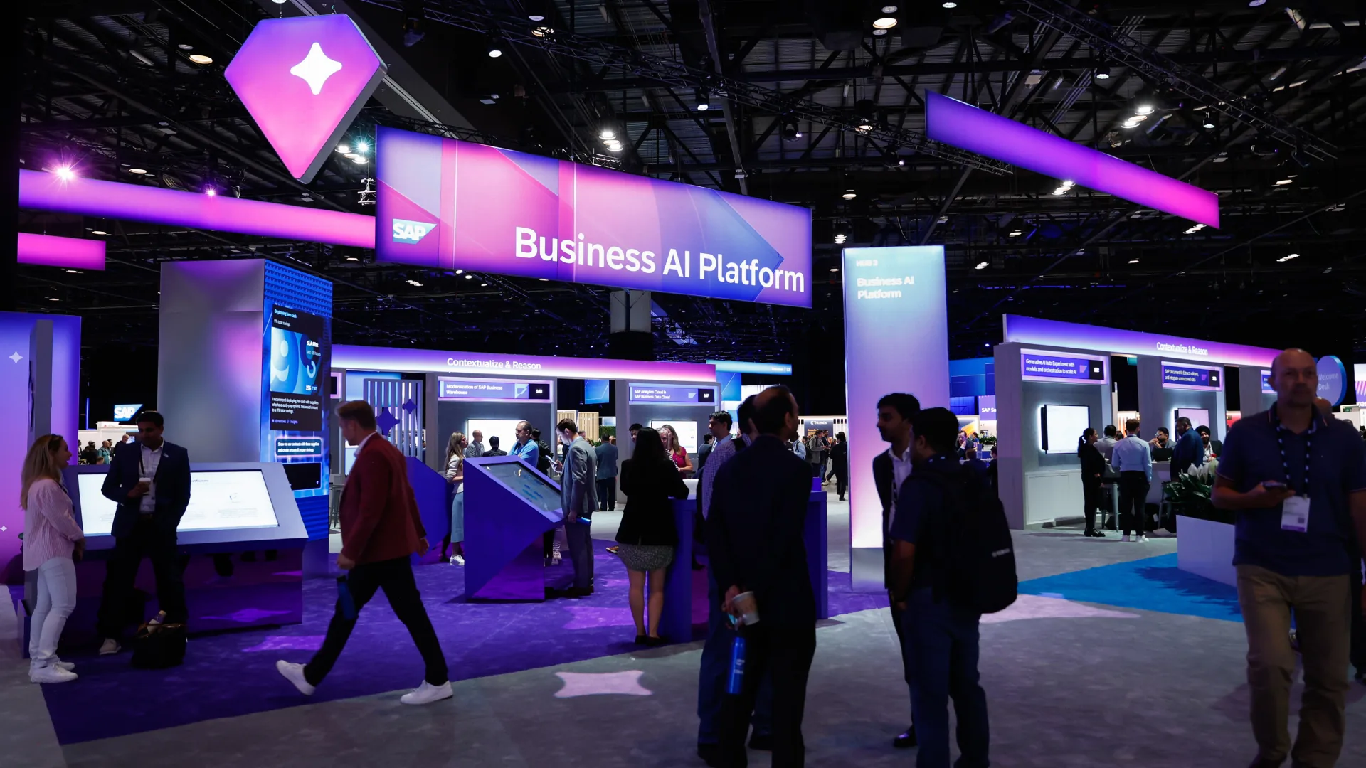Attendees explore touchscreen demos beneath the Business AI Platform sign on the show floor