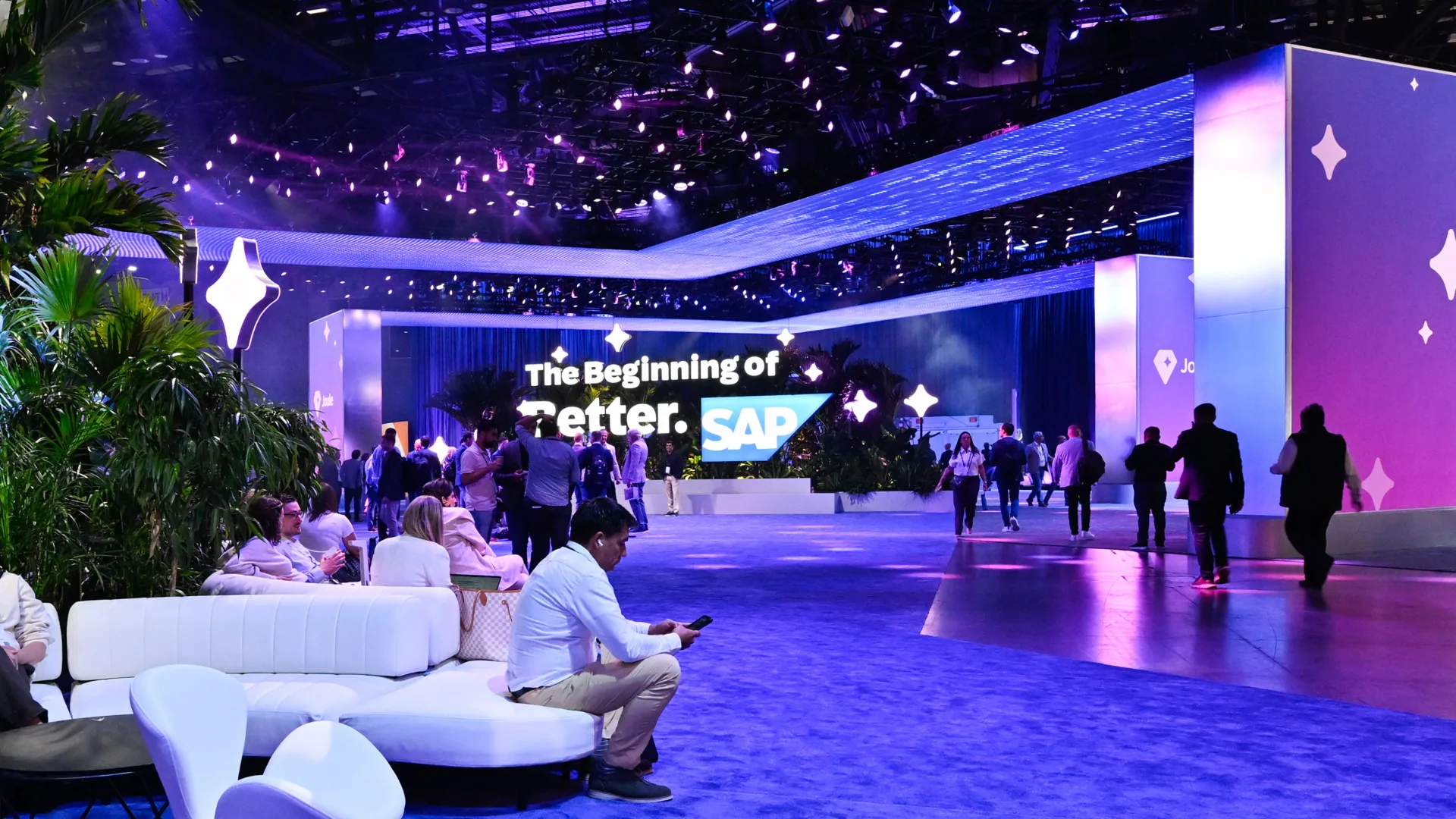 Attendees rest on white lounge seating near Joule towers at the immersive entrance
