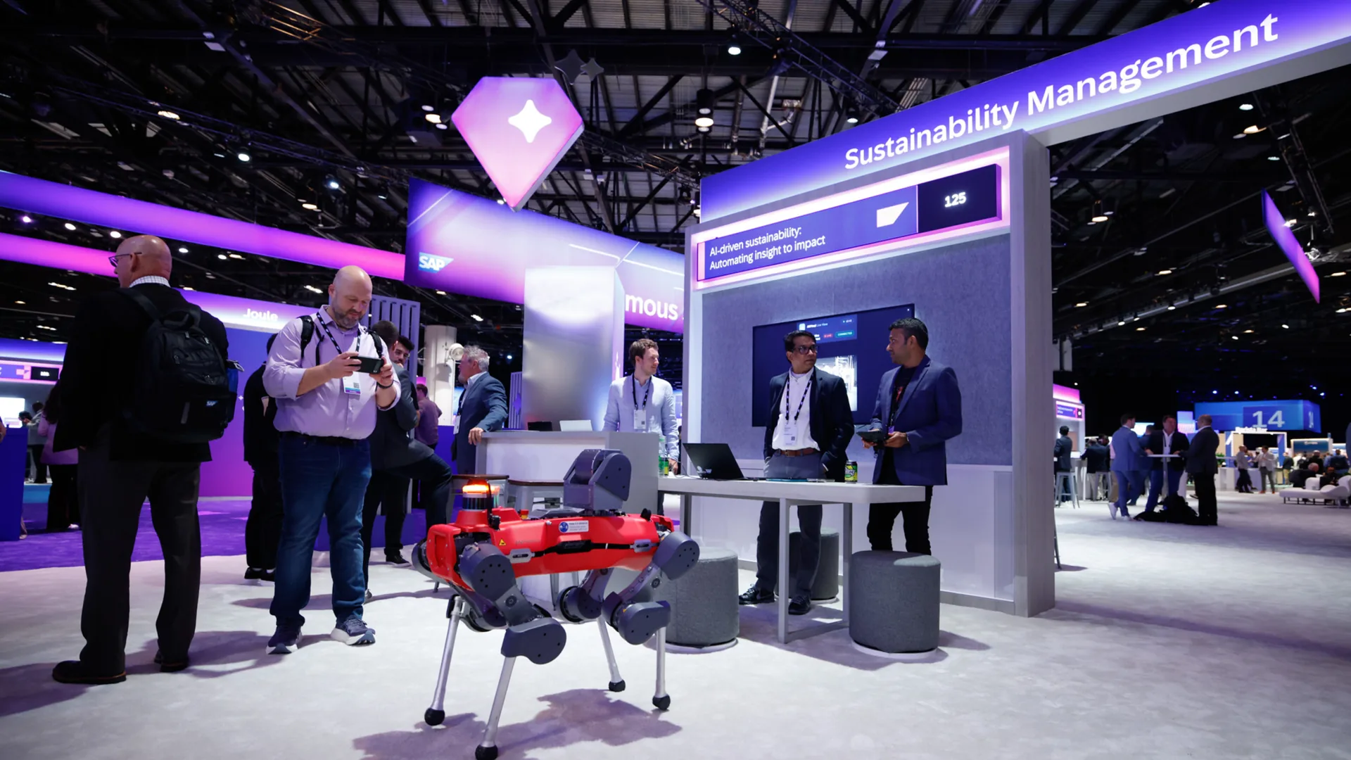 Attendees gather around a robot dog at the Sustainability Management hub designed by Sparks