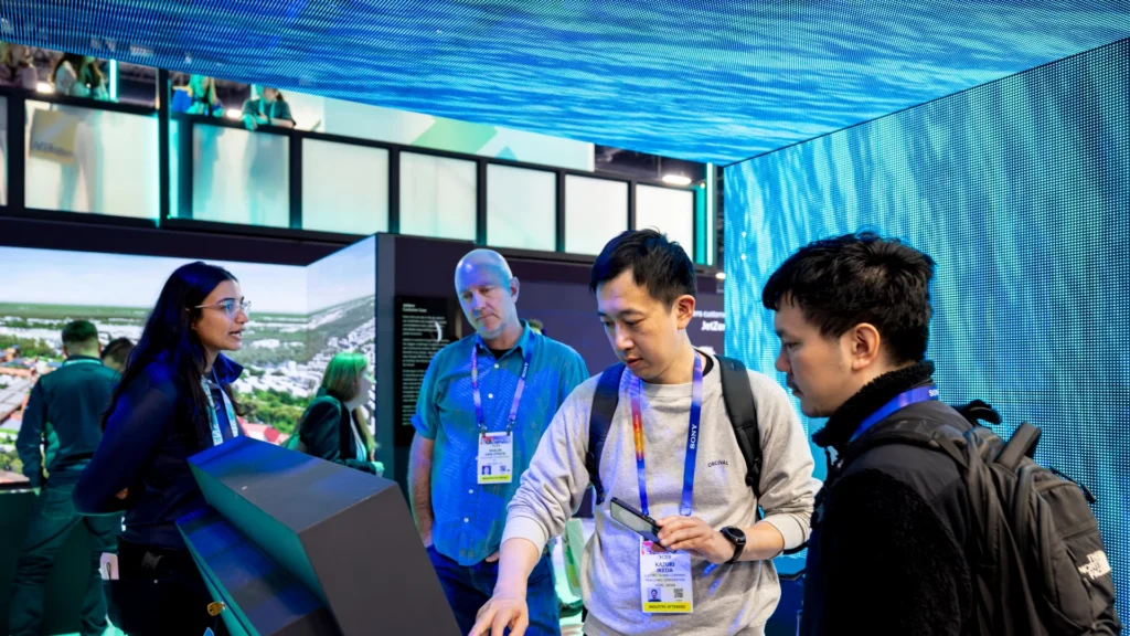 Guide shows three attendees a kiosk beneath a water-pattern LED canopy