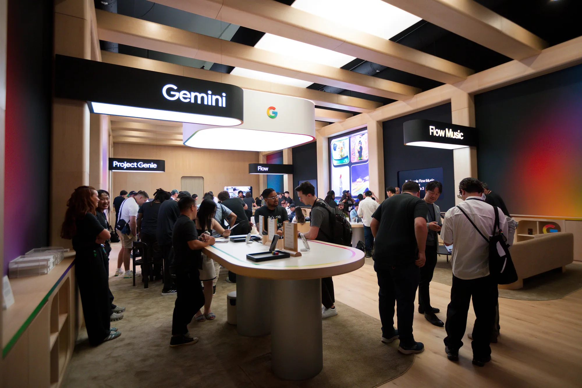 Attendees gather around a central demo table beneath Gemini, Google and Flow Music signs