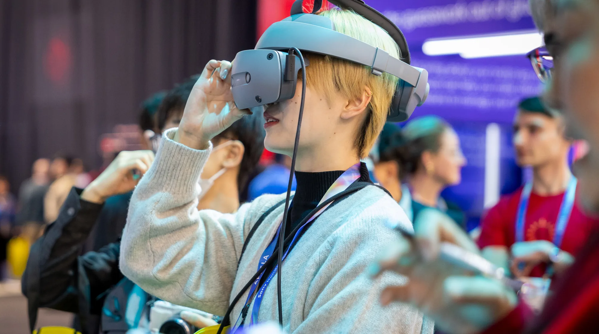 Conference attendee trying an XR headset during a hands-on technology demo while other guests look on.