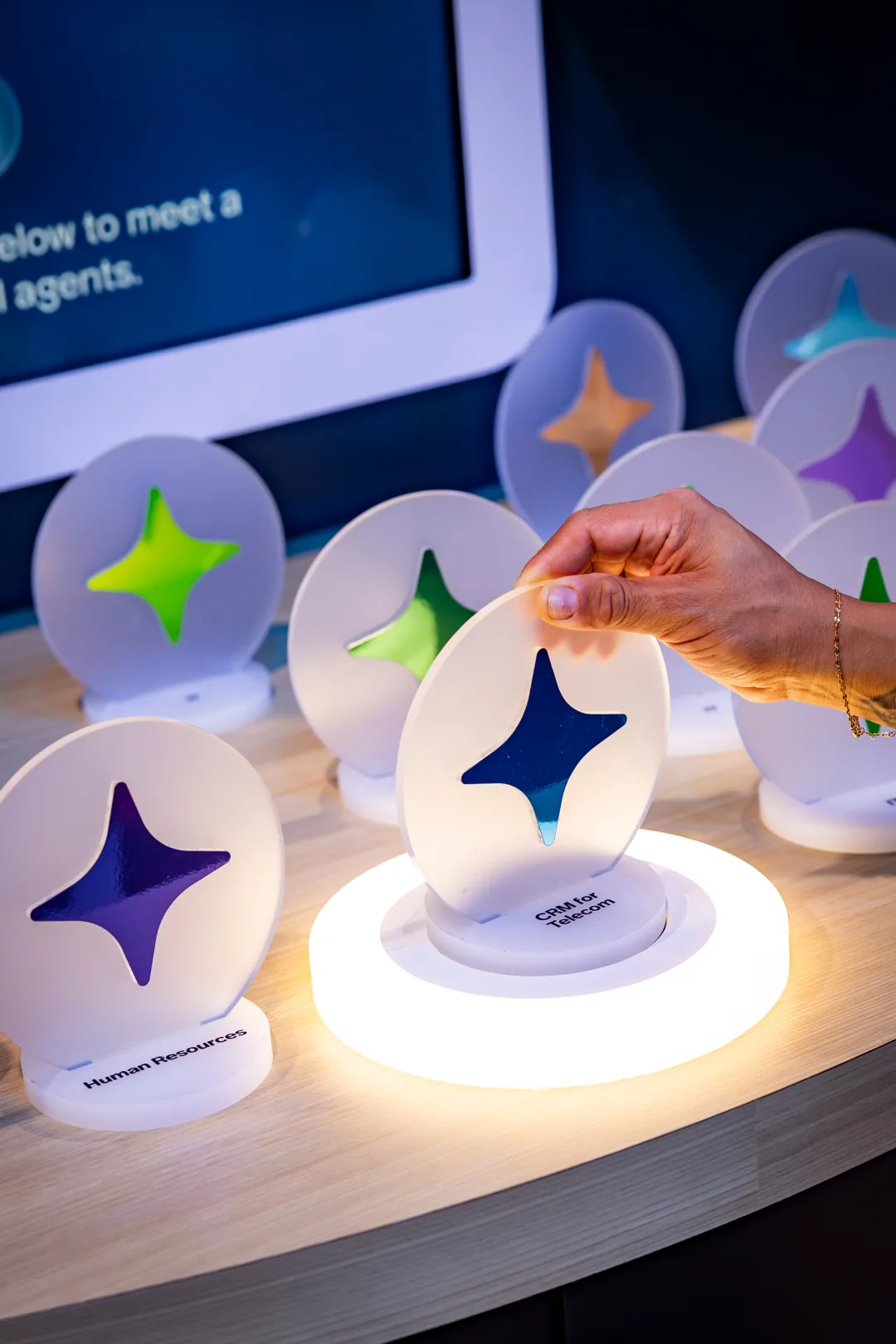 Hand places a frosted sparkle disc on a lit base to meet AI agents