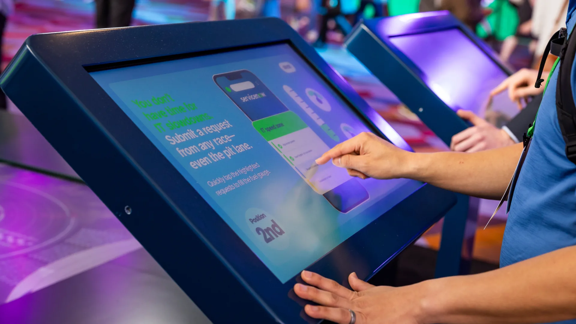 Attendee taps a request into a racing-themed touchscreen game set in the pit lane