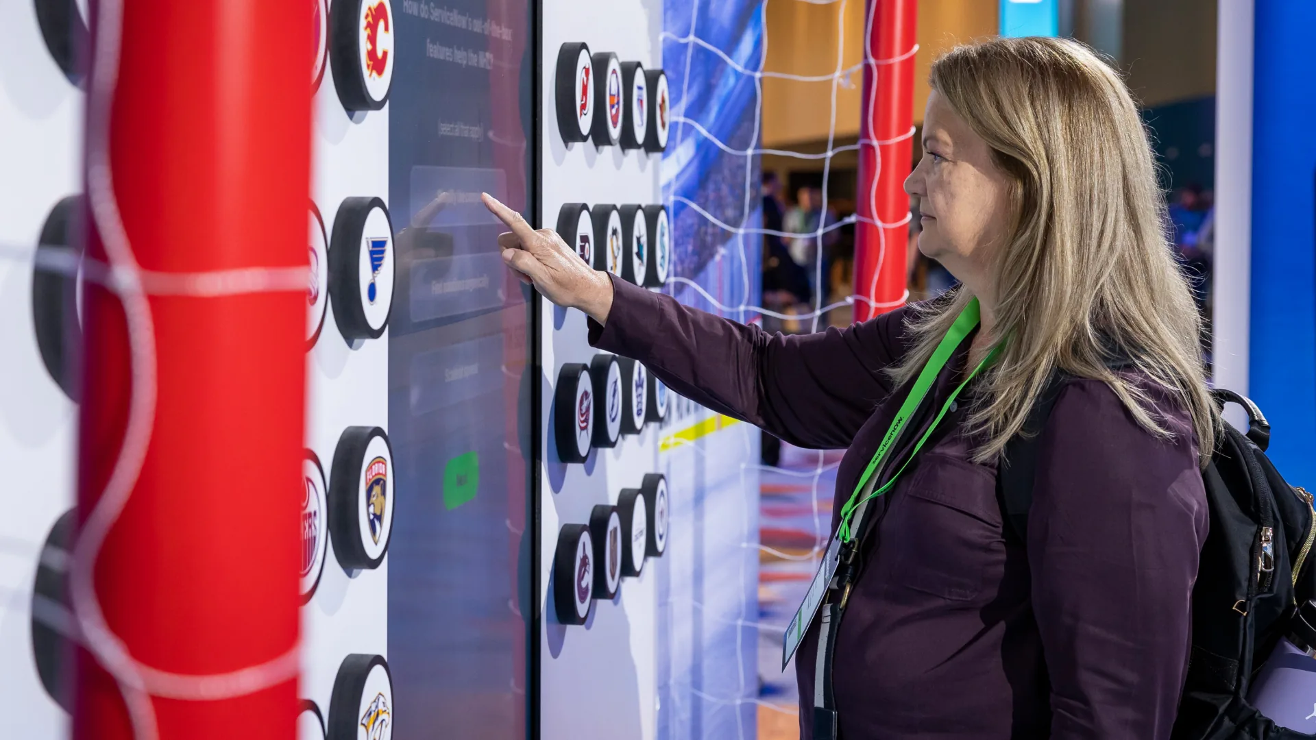 Attendee taps a touchscreen framed by hockey goal posts and NHL team pucks