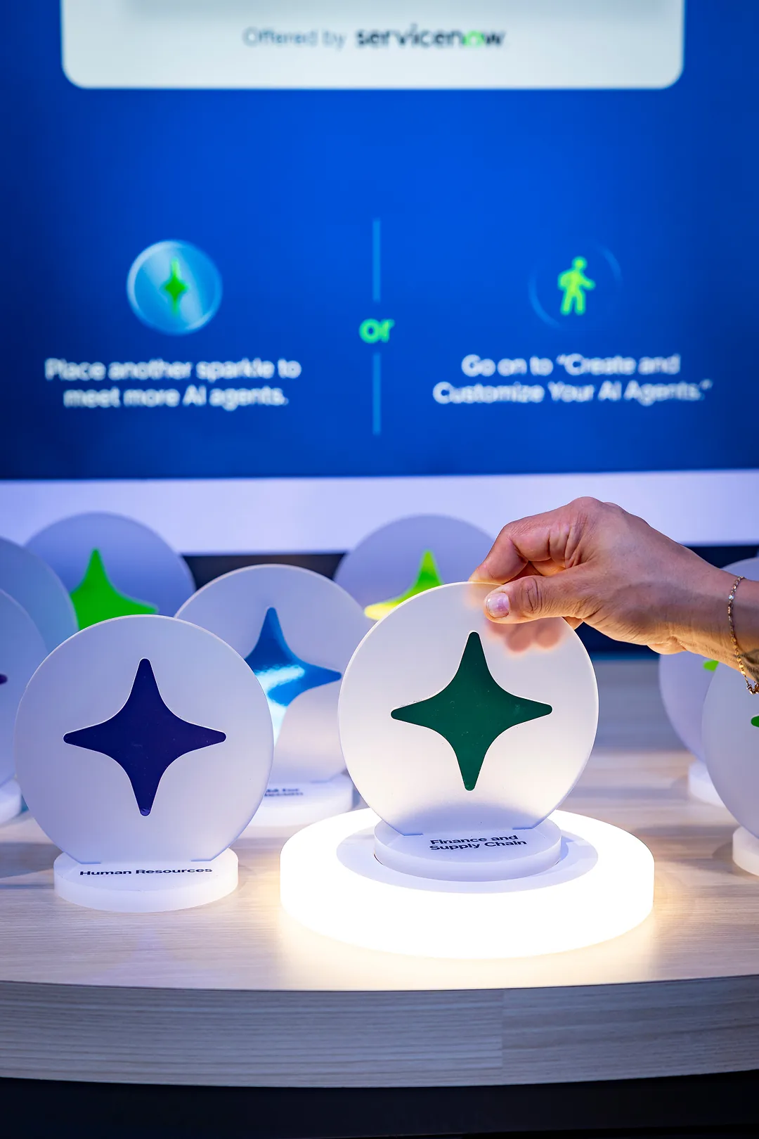 Close-up of a hand placing a green sparkle disc on a lit pedestal